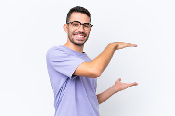 Young caucasian man isolated on white background holding copyspace to insert an ad