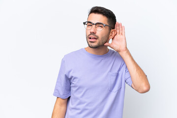 Young caucasian man isolated on white background listening to something by putting hand on the ear