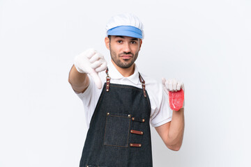 Butcher caucasian man wearing an apron and serving fresh cut meat over isolated white background showing thumb down with negative expression