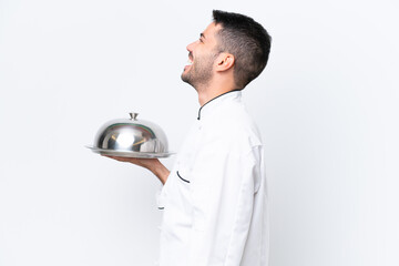 Young chef with tray isolated on white background laughing in lateral position