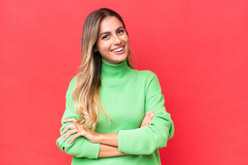 Young Uruguayan woman isolated on red background keeping the arms crossed in frontal position