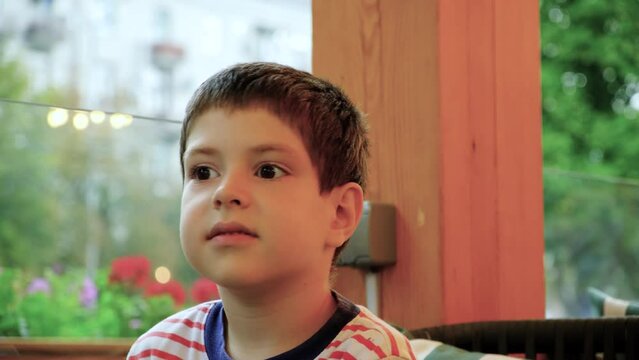A fidget six-year-old child cannot sit in one place, spins around sitting in a cafe