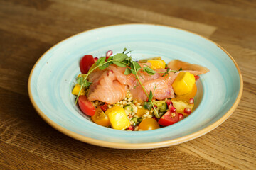 Tabbouleh salad with mango, colorful tomatoes and smoked salmon