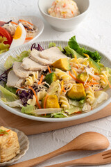 Fresh avocado lettuce salad bowl with chicken meat in a plate on white table background.