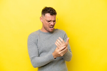 Young caucasian handsome man isolated on yellow background suffering from pain in hands