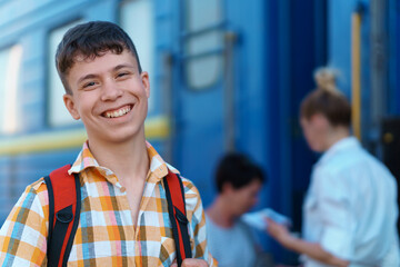 a student poses at a railway station, a teenage boy walks along the platform to the train, he has a backpack and books, goes to study, the concept of education