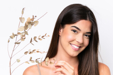 Fototapeta premium Young Brazilian woman isolated on white background holding a eucalyptus branch while smiling. Close up portrait