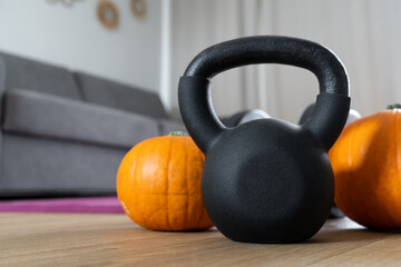 Kettlebell gym exercise equipment and autumn pumpkins. Healthy fitness lifestyle. House workout training concept for Halloween or Thanksgiving. Staying in shape at home during fall season. - Powered by Adobe