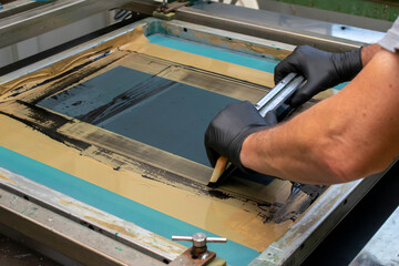 hand made screen printing, squeezing the paint with a squeegee