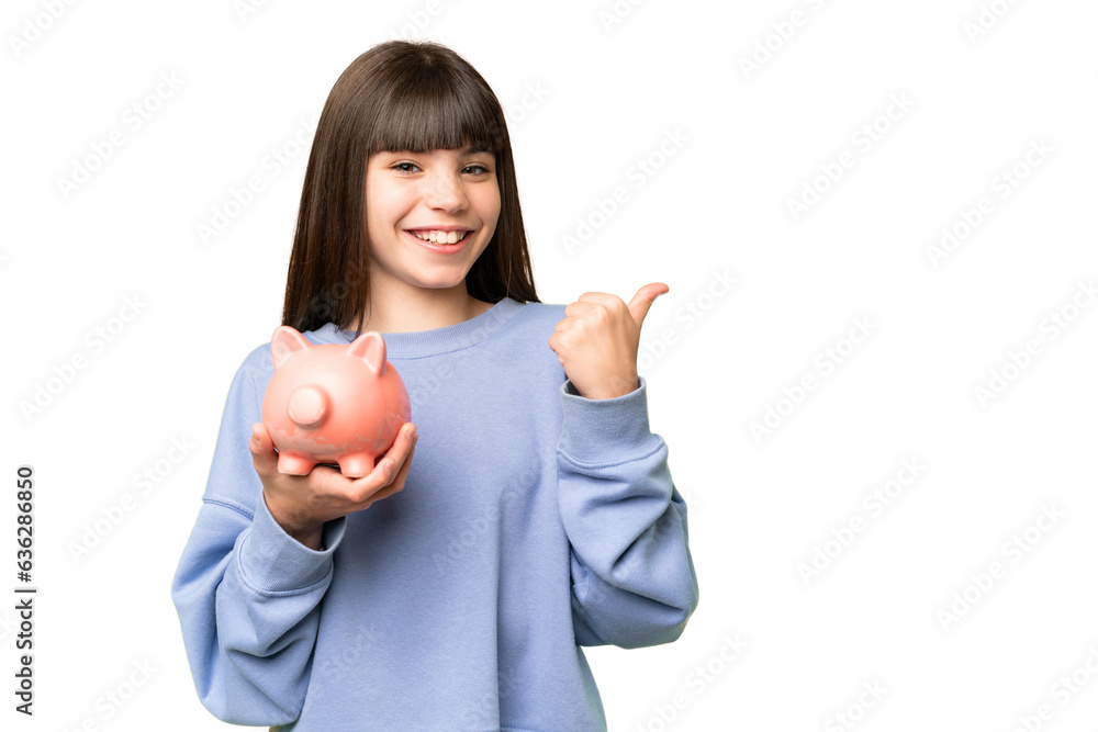 Wall mural Little girl holding a piggybank over isolated chroma key background pointing to the side to present a product