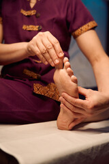 Qualified spa therapist giving Thai foot massage to client