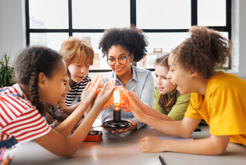 Fototapeta na wymiar Multiethnic teacher and kids studying electricity and incandescent light bulb at physics lesson.