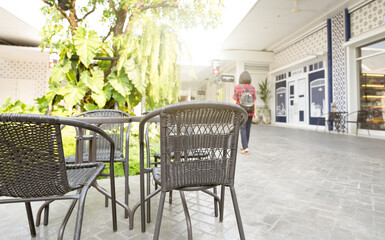 Outdoor table of coffee cafe and reataurant in summer day. Summer terrace on city street. Empty outside tables and chairs of outdoor cafe on blur green garden. Cozy outdoor zone cafe and restaurant.