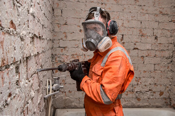 Construction  worker wearing full face respirator mask and ear defenders for working with hammer...