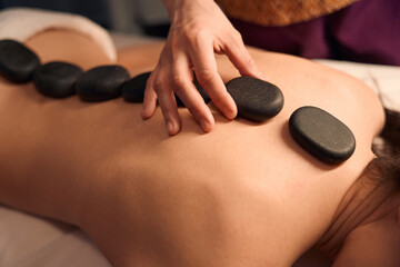 Spa therapist relieving female patient of backache during massotherapy session