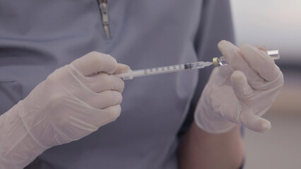 Doctor holding a syringe with blue liquid, close-up.