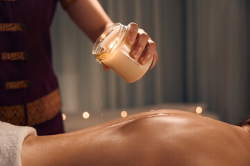 Masseuse preparing client for aromatherapy candle massage