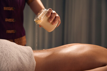 Massotherapist preparing woman for aromatherapy candle massage session