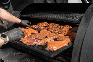 Chef hand cooking grilled beef meat in BBQ smoker.