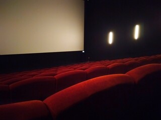 Empty movie theather with empty seats and blank screen. Side view, rear audience point of view 