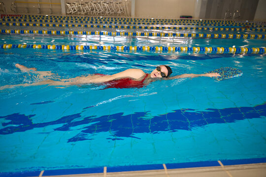 Young female swimmer is performing sidestroke in pool