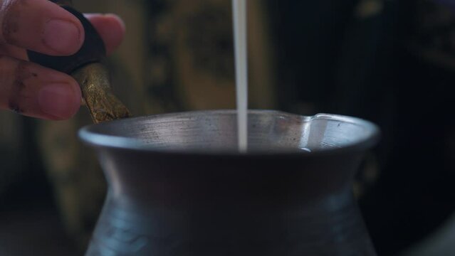Indian woman hands pour milk into masala chai tea making. Close up.