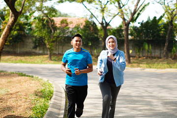 Young muslim couple happy together running at green summer park. Man and woman in hijab doing...