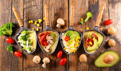 raclette tray with cheese, ham and vegetables- traditional french raclette cheese party