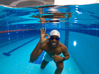 Cheerful athlete approving his underwater workout in swimming pool