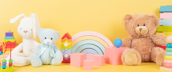 Educational kids toys collection. Teddy bear, wood rainbow, xylophone, wooden educational baby toys on yellow background. Front view - obrazy, fototapety, plakaty