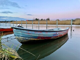 Old fishing boat, rowboat, dinghy in a small harbor. Beautiful sunset.