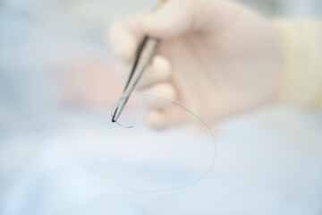 Surgeon holds in his hand a surgical needle