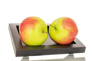 Two organic juicy apples on a wooden black tray, macro, isolated on white background.