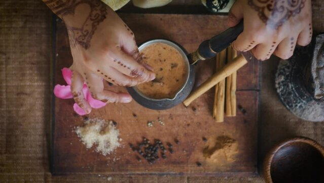 Indian woman hands stirring masala chai tea making with teaspoon. Close up.