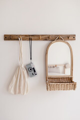 Wood hook rack with retro film camera, mirror and cotton canvas bag on white wall on the modern style bedroom background. Smart organisation storage idea. Eco friendly life. Minimal interior decor.