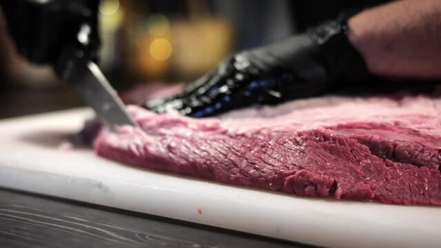 Male chef hands cutting fresh organic raw meat piece for barbecue cooking use knife slow motion