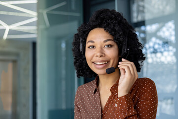 Close-up portrait of businesswoman inside office with headset phone, employee smiling and looking at camera at workplace, call center customer service.