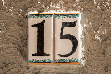 Faience enameled decorated plate of number of street address with number 15 closeup