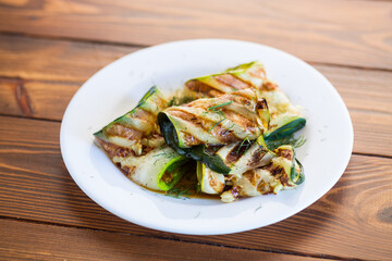 Grilled zucchini pieces with garlic sauce in a white plate.