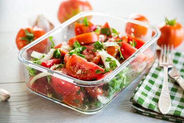 Spicy snack tomatoes with garlic, herbs, seasonings and onions in a glass bowl .