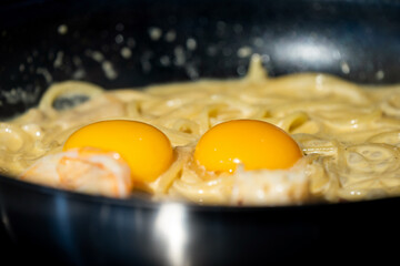 Close up macro to yolk in Creamy fried and boiled Spaghetti pasta in hot pan.