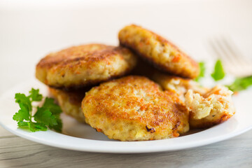 Cooked fried fish cutlets in a plate with herbs.