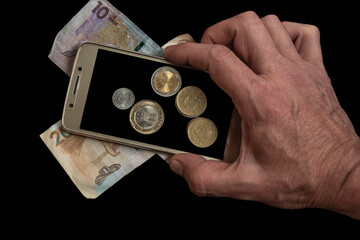 Businessman holding Colombian coins on the background of a cell phone screen