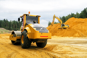 a crawler excavator loads sand into a truck. Large hills and heaps of sand, gravel, crushed stone...