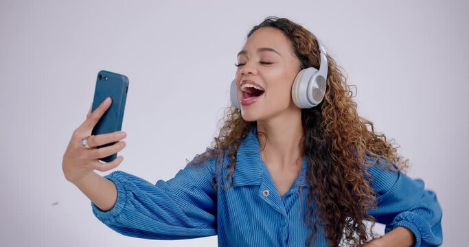 Happy woman, peace or headphones for selfie in studio for video call, vlog and social media post on white background. Profile picture, gen z model and v sign with tongue out, kiss emoji and broadcast