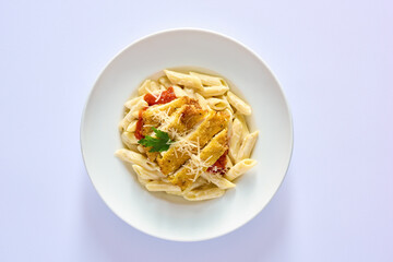 Penne pasta with red sauce, chicken strips, and shredded parmesan, top view on white background