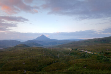 Naklejka premium The western slope of Mount Ben Stack and the road through the valley at dawn. North West Sutherland, Scotland