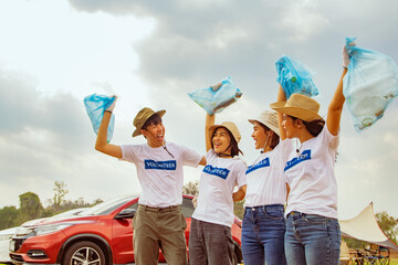 Group of happy asian young student people driving car for volunteer trip wearing white shirts celebrating success together team collecting plastic bottles in bags and cleaning natural attractions. - obrazy, fototapety, plakaty
