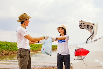 Asian volunteer couple willing to voluntarily collect garbage and clean up in natural tourist...