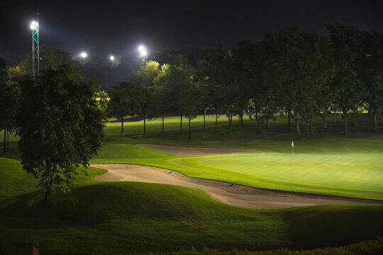 Beautiful dark night view of the golf course, Bunkers sand and green grass, garden background In the light of the spotlight underexposure view.